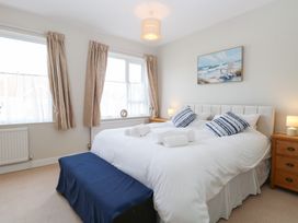A bedroom with a large bed two striped pillows three rolled towels wooden bedside tables and two windows at 34 North Denes Road in Great Yarmouth