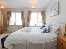 A bedroom with a double bed pillows and rolled towels by two windows with curtains at 34 North Denes Road in Great Yarmouth