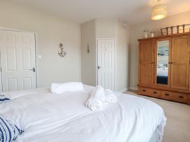 A bedroom with a bed with white linens two doors a wooden wardrobe and a wall decoration at 34 North Denes Road Great Yarmouth