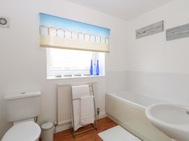 A bathroom with a toilet towel rack bathtub sink and window with a printed blind at 34 North Denes Road in Great Yarmouth