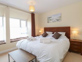 A bedroom with a large bed white bedding brown pillows bedside tables with lamps and a window seat at 34 North Denes Road in Great Yarmouth