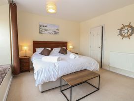 A bedroom with a double bed and brown pillows two bedside tables with lamps a painting above the bed and a wooden table at 34 North Denes Road in Great Yarmouth
