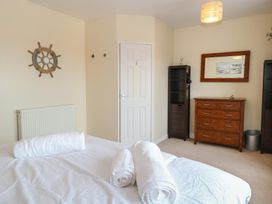 A bedroom with a bed and rolled towels a wooden dresser a mirror and a door at 34 North Denes Road in Great Yarmouth