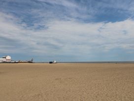A sandy beach with a pier and wind turbines in the distance at 34 North Denes Road in Great Yarmouth