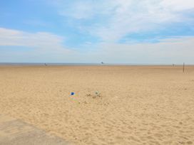 A sandy beach with a few scattered toys near the shore and a ship in the sea at 34 North Denes Road in Great Yarmouth