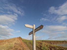 A wooden signpost on a grassy path with directions to Castle Bay and Coast Path at Dunskey Way in Portpatrick