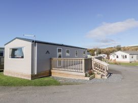 A mobile home with a wooden deck and railing on a grassy plot in a residential area at Dunskey Way in Portpatrick