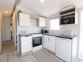 A kitchen with white cabinets stove kettle toaster microwave and a small fridge at Dunskey Way in Portpatrick