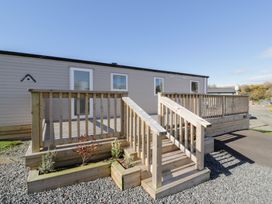 A wooden deck with stairs and railing outside a single-story unit at Dunskey Way in Portpatrick