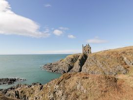A coastal landscape with rocky cliffs and a stone ruin on a hill overlooking the ocean at Dunskey Way in Portpatrick