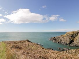 A coastal landscape with rocky cliffs and water under a partly cloudy sky at Dunskey Way in Portpatrick