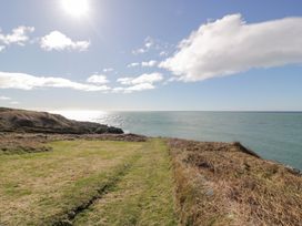 A grassy coastal path overlooking the ocean under a sunny sky at Dunskey Way in Portpatrick