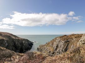 A rocky coastal landscape with cliffs and ocean under a partly cloudy sky at Dunskey Way in Portpatrick