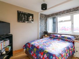 A bedroom with a bed with floral bedding a TV on a stand and a window with vertical blinds at 271 California Sands Estate in California Norfolk