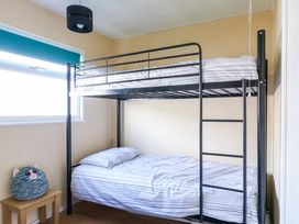 A bedroom with a metal bunk bed and a small wooden stool with a cat pillow by the window at 271 California Sands Estate in California Norfolk