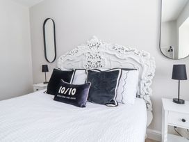 A bedroom with an ornate white headboard black pillows black lamps and two mirrors at Ty Blodau near Prestatyn