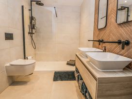 A bathroom with a walk-in shower a wall-mounted toilet and a double sink vanity at Ty Blodau near Prestatyn