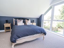 A bedroom with a bed and two bedside tables with lamps near a large window at Ty Blodau near Prestatyn
