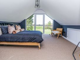 A bedroom with a large bed and pillows near a window with a view of trees and grass at Ty Blodau near Prestatyn