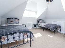 A bedroom with two single beds and small side tables near a window at Ty Blodau near Prestatyn