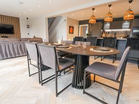 A dining table with chairs and place settings in an open-plan kitchen and living area at Ty Blodau near Prestatyn