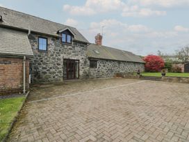A stone house with paved driveway and garden with red bush at Y Granar in Conwy