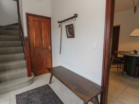 An entryway with carpeted stairs a wooden door a wooden bench a small mirror a walking stick and a rug at Y Granar in Conwy