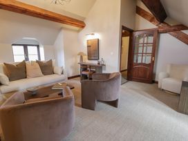 A living room with two brown chairs a white sofa with cushions a wooden coffee table a desk with a chair and lamp wooden beams on the ceiling at Y Granar in Conwy
