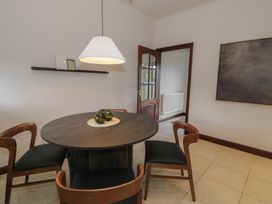 A dining area with a round wooden table and four chairs under a hanging lamp at Y Granar in Conwy