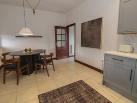 A dining area with a round table and four chairs next to a kitchen counter with a toaster in Y Granar in Conwy