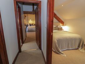 A hallway with two bedrooms visible one with a bed and lamp the other with a bed and light fixture at Y Granar in Conwy