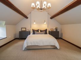 A bedroom with a bed and two dressers under wooden ceiling beams at Y Granar in Conwy