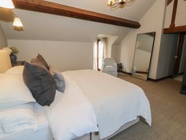 A bedroom with a bed and pillows a chair a full length mirror and a lamp at Y Granar in Conwy