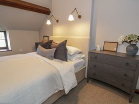 A bedroom with a bed and pillows next to a wooden dresser with vases and picture frames at Y Granar in Conwy