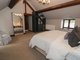 A bedroom with a bed and pillows a large mirror an armchair and a black shelving unit with baskets at Y Granar Conwy