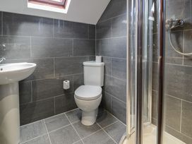 A bathroom with a toilet sink and shower with glass doors at Y Granar in Conwy
