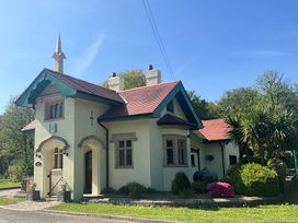 A cream colored house with a red roof and green trim surrounded by plants and trees at Hafod Lodge in Hensol near Pontyclun