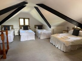 A bedroom with four beds under a sloped ceiling with black beams at Hafod Lodge in Hensol near Pontyclun