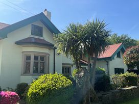 A house with a bay window surrounded by bushes and trees at Hafod Lodge in Hensol near Pontyclun