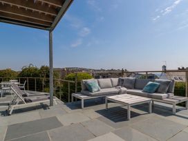 An outdoor patio with a sectional sofa, coffee table, two lounge chairs, and a dining table with chairs at The Old Harbour Masters House in Fowey