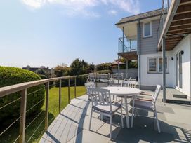 An outdoor patio with a round table and chairs next to a house with balconies and railing at The Old Harbour Masters House in Fowey
