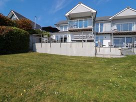 A modern house with balconies and outdoor seating on a grassy lawn at The Old Harbour Masters House in Fowey