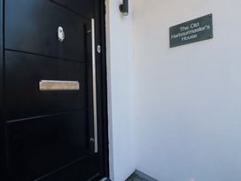A black front door with a silver handle and mail slot beside a white wall with a sign that reads The Old Harbourmasters House at The Old Harbour Masters House in Fowey