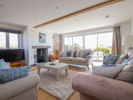 A living room with sofas a coffee table a fireplace and large sliding doors at The Old Harbour Masters House in Fowey
