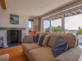 A living room with a beige sofa and blue cushions near a fireplace and large window at The Old Harbour Masters House in Fowey