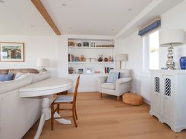 A living room with a beige armchair bookshelf and wooden chair at The Old Harbour Masters House in Fowey
