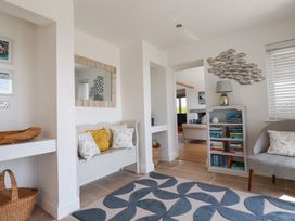 A room with a bench with cushions a bookshelf with books and a lamp a chair and a patterned rug at The Old Harbour Masters House in Fowey