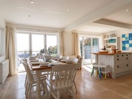 A dining area with a wooden table set for eight and a kitchen island with two small chairs at The Old Harbour Masters House in Fowey