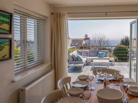 A dining area with a set table and an outdoor patio with seating overlooking the sea at The Old Harbour Masters House in Fowey