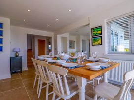 A dining room with a wooden table set with plates bowls and glasses surrounded by white chairs at The Old Harbour Masters House in Fowey